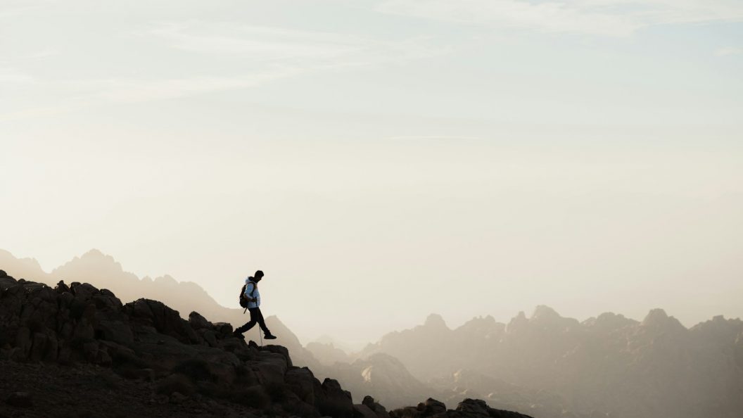 a man running up a mountain with a sky background